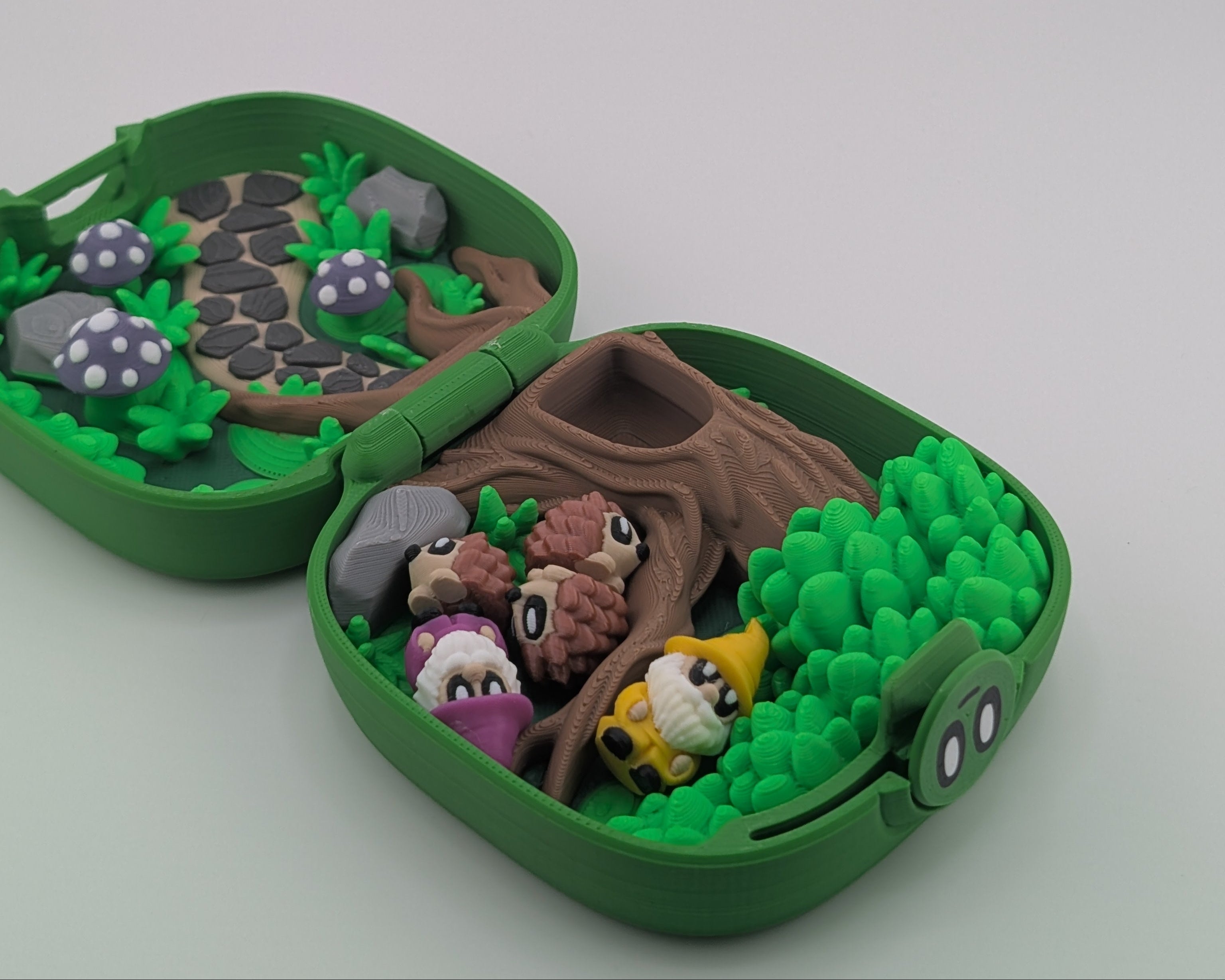 Green toy box with small figurines and natural elements on a light gray background