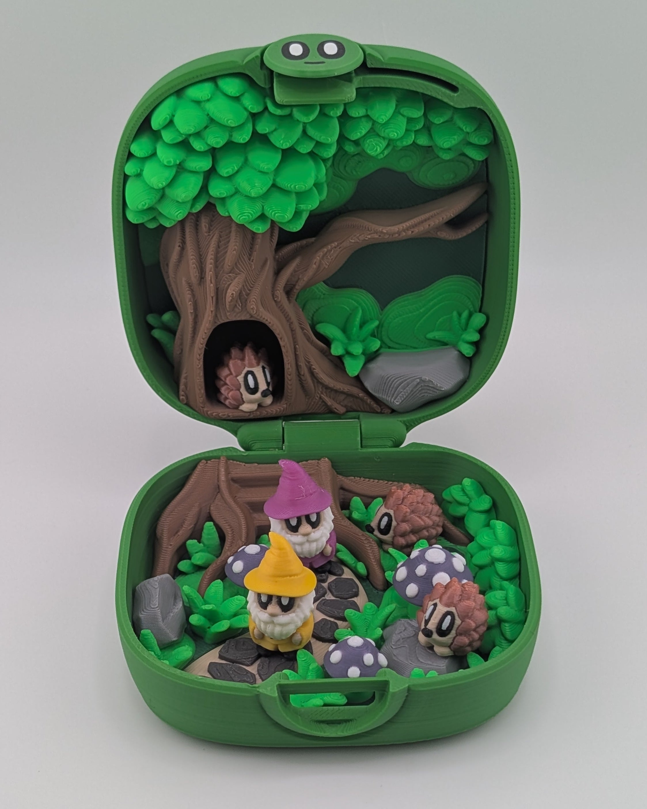 Green toy case with a forest scene and small characters on a white background