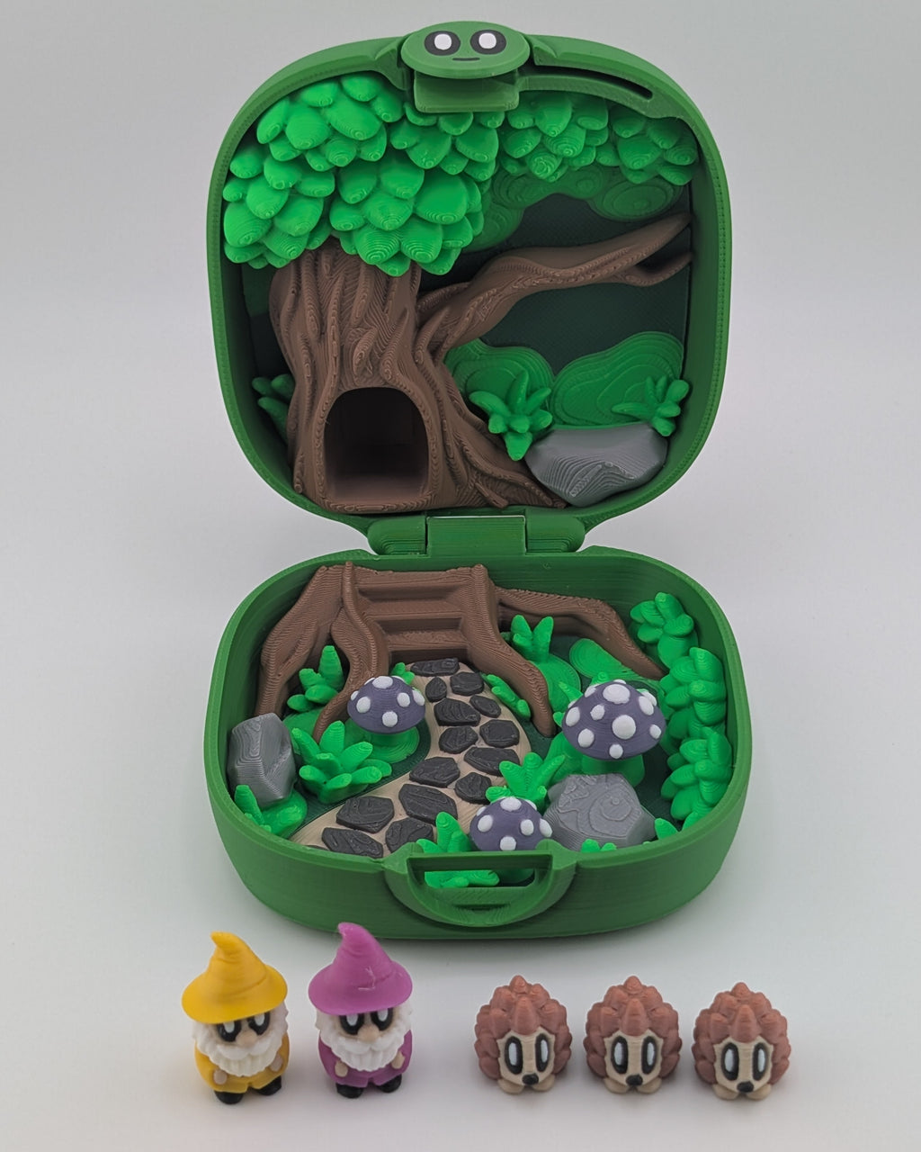 Green toy case with a forest design and small figurines on a white background