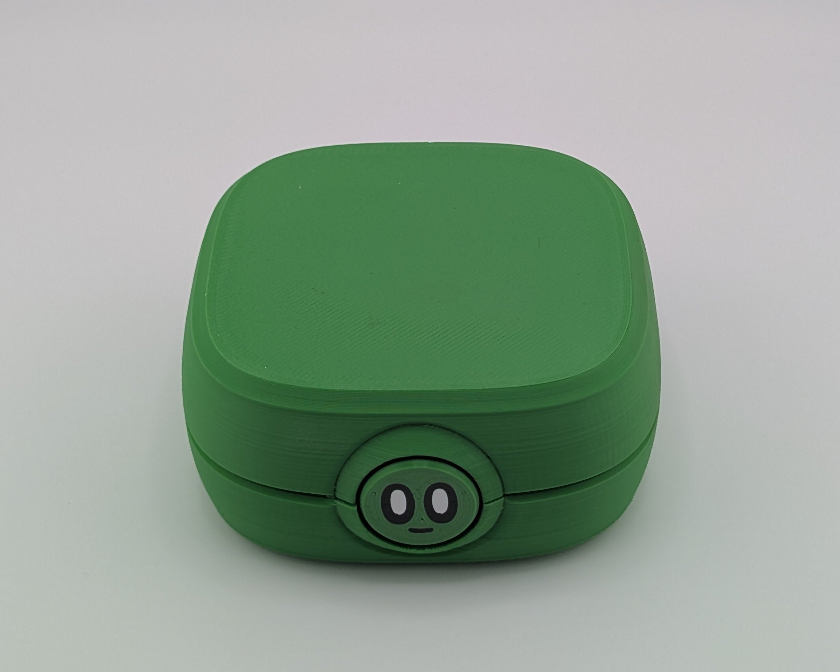 Green square-shaped container with a circular base on a light gray background