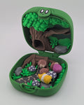 Green toy case with a treehouse and small figurines on a white background When you first open