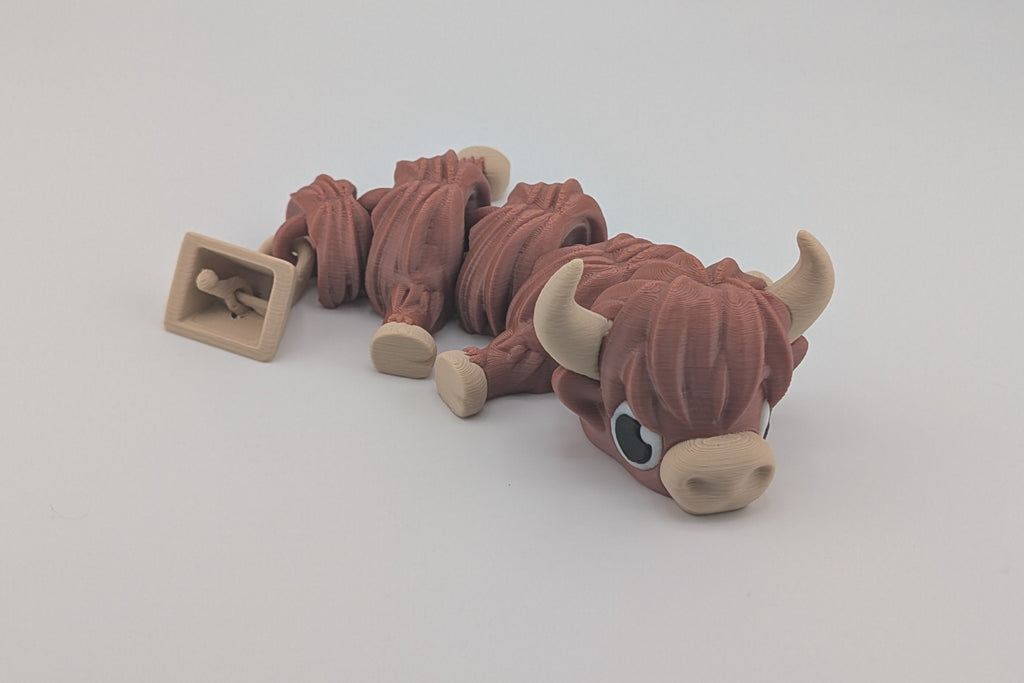 Plush toy Highland Cow with a bell on a white background