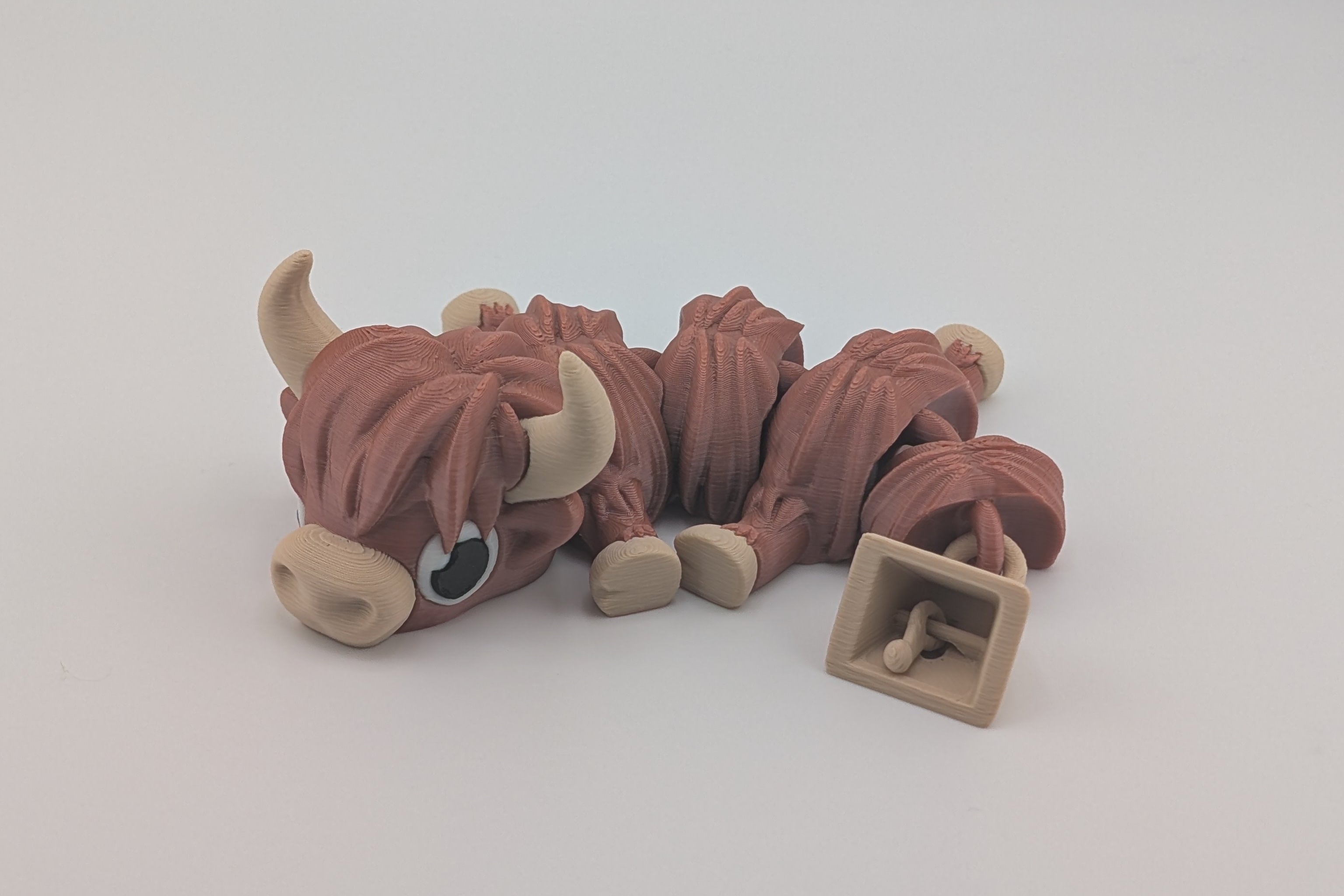 Small toy figure of a Highland Cow on a white background