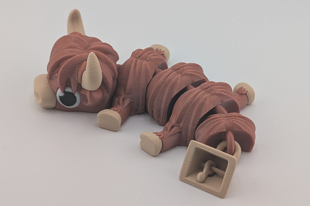 Small brown toy Highland Cow on a white background