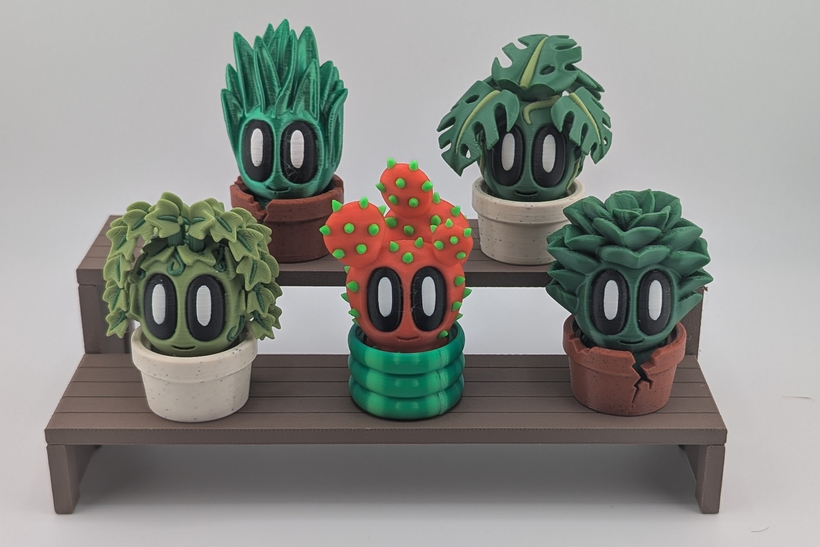 Set of cartoonish cactus figurines on a wooden stand against a plain background