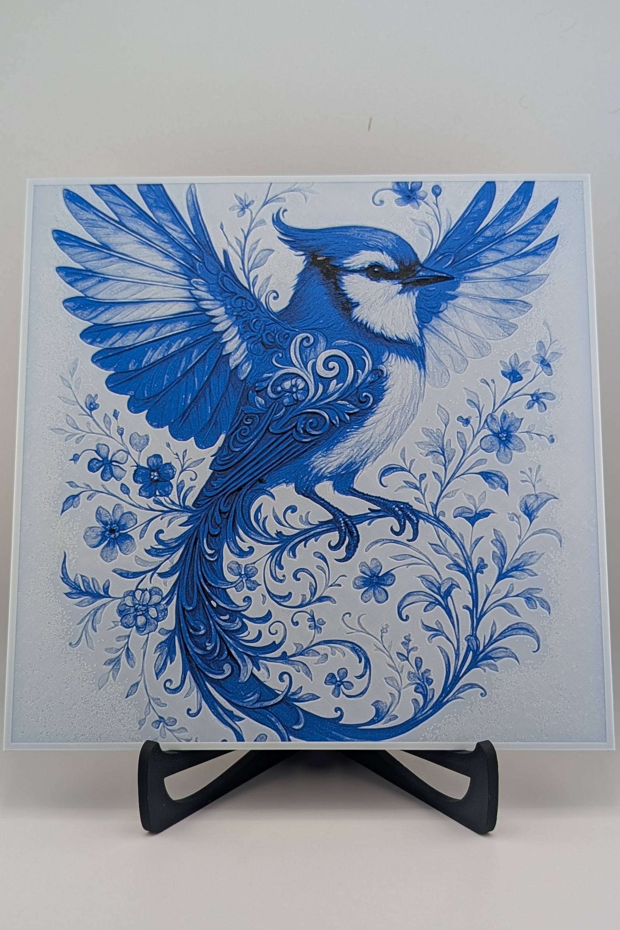 Blue and white decorative card with a bird design on a stand against a white background