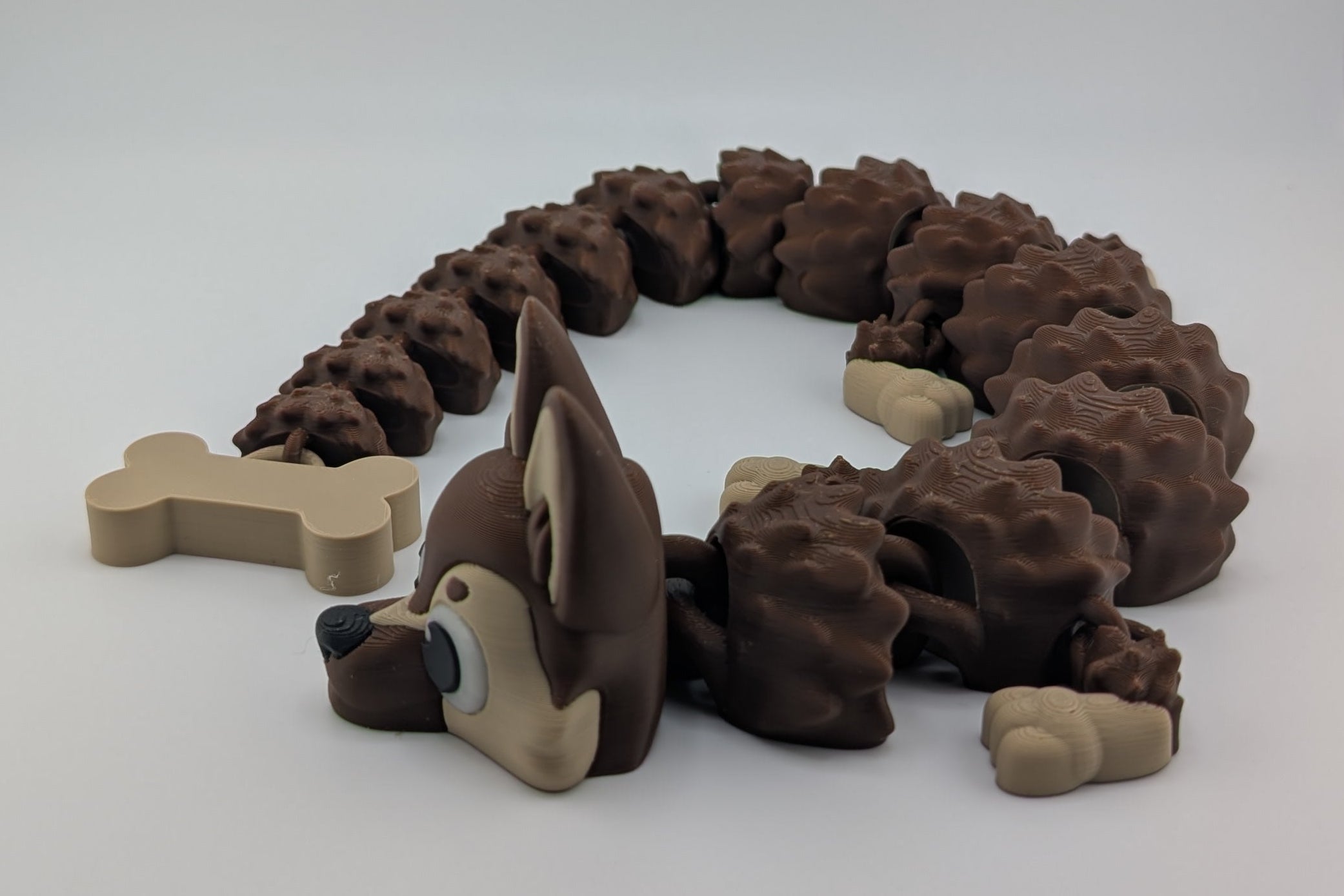 Dog toy shaped like a snake with bone pieces on a white background