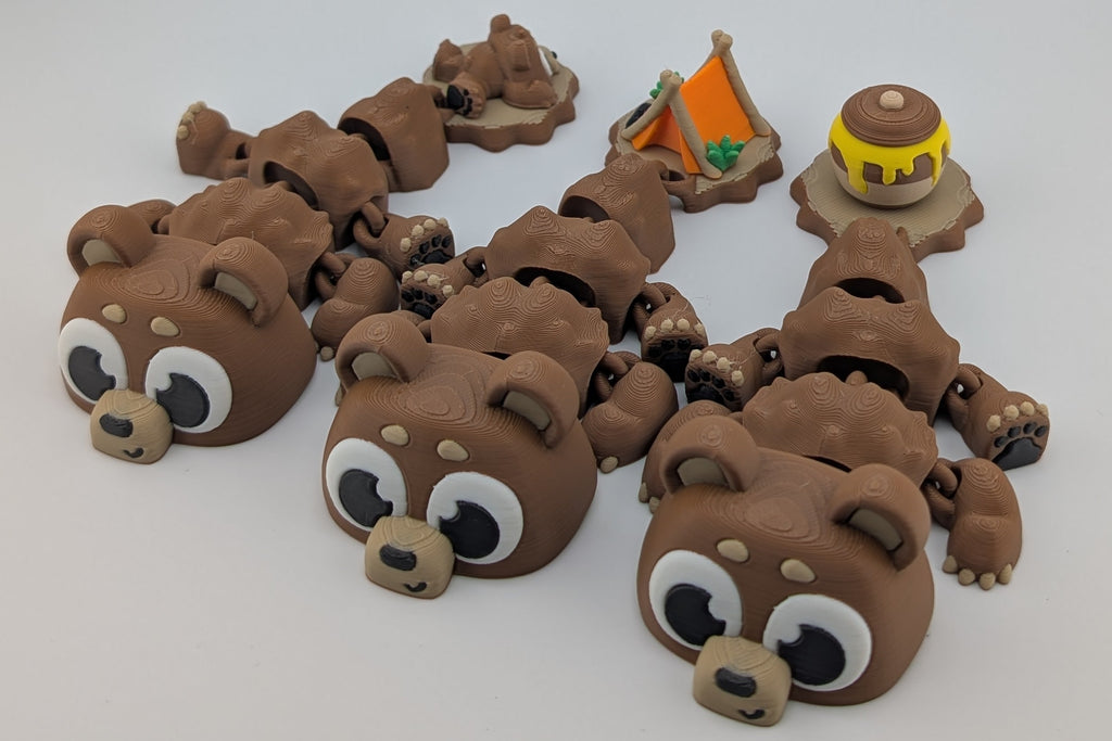 Small brown bear figurines with a tent and barrel on a white background