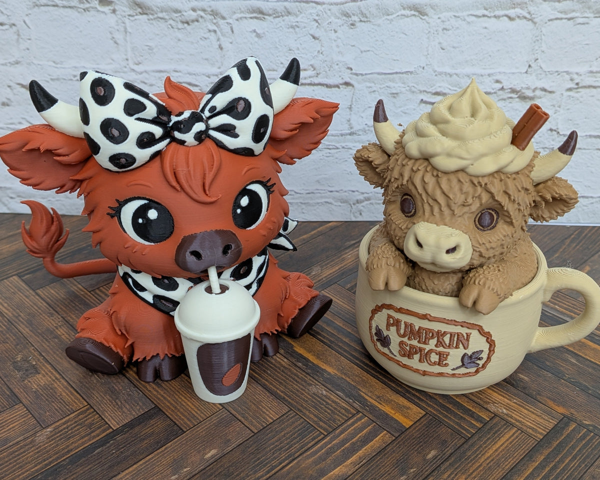 Two cute animal figurines sitting on a wooden surface against a white brick wall. On the left is an orange cow-like character wearing a black-and-white cow-print bow and scarf, holding a small drink cup.